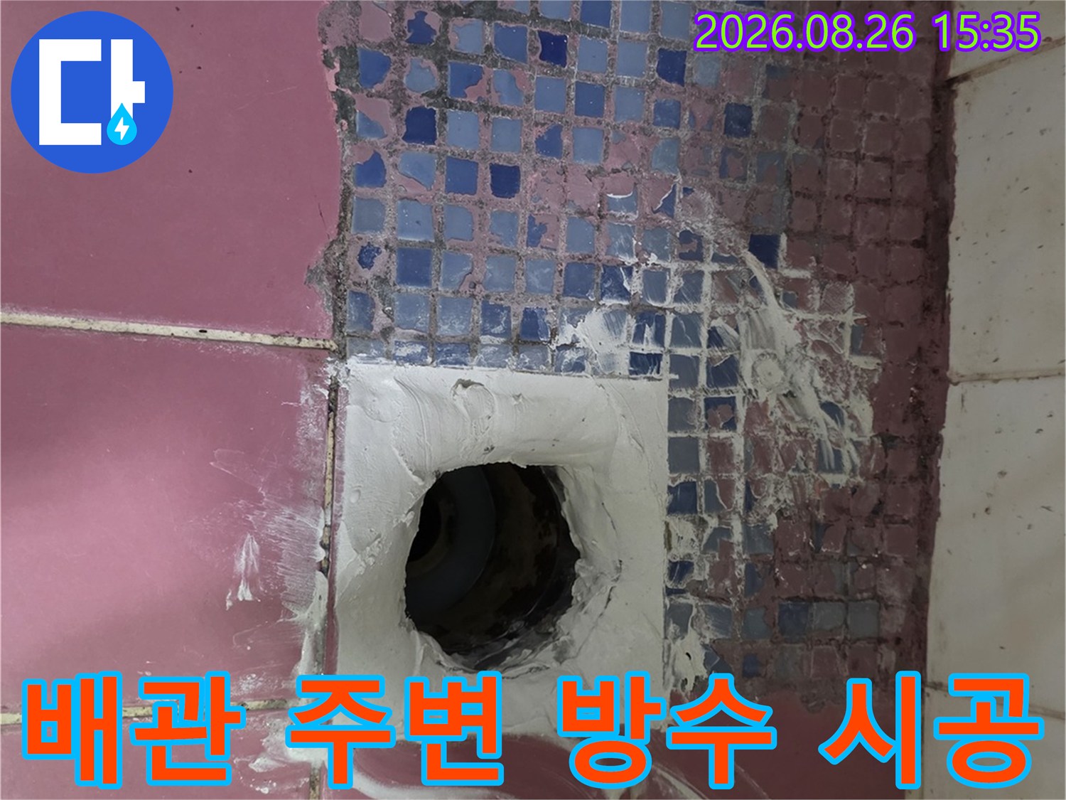 하수구 배관 주위의 훼손된 타일과 백시멘트 작업 현장입니다.
