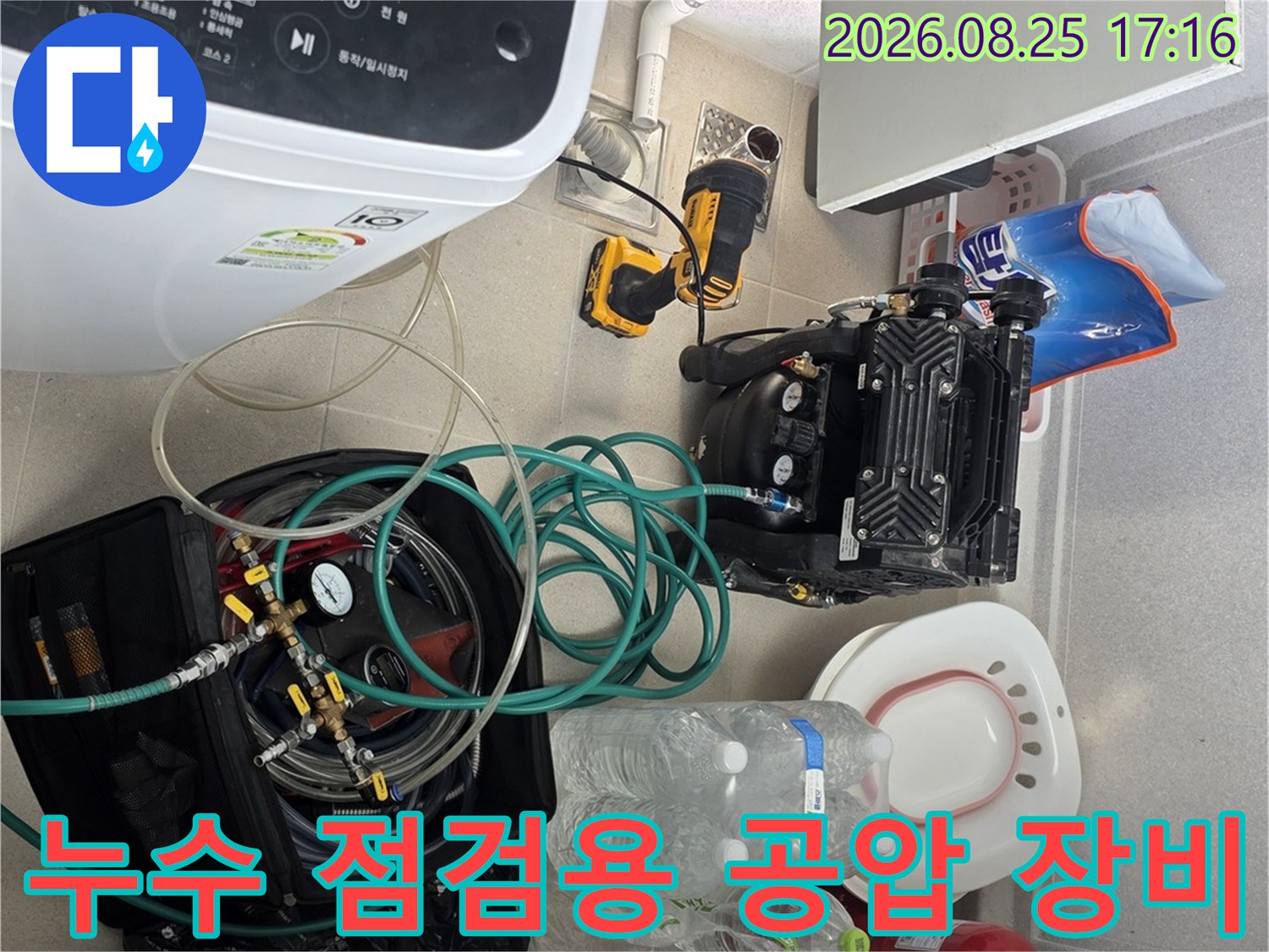 세탁실 바닥에 배치된 배관 압력 측정 기계와 연결 호스 및 수리 도구들