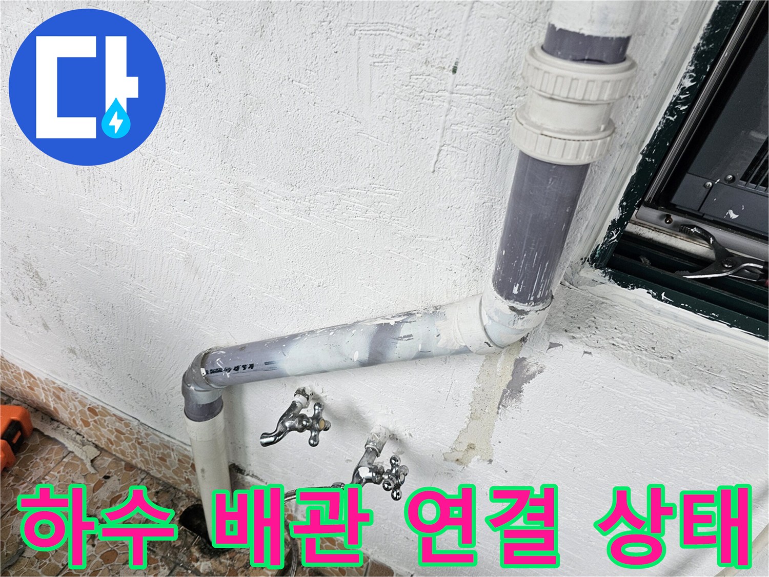 벽면 하수 배관과 수도 부속의 결합 부위 근접 사진