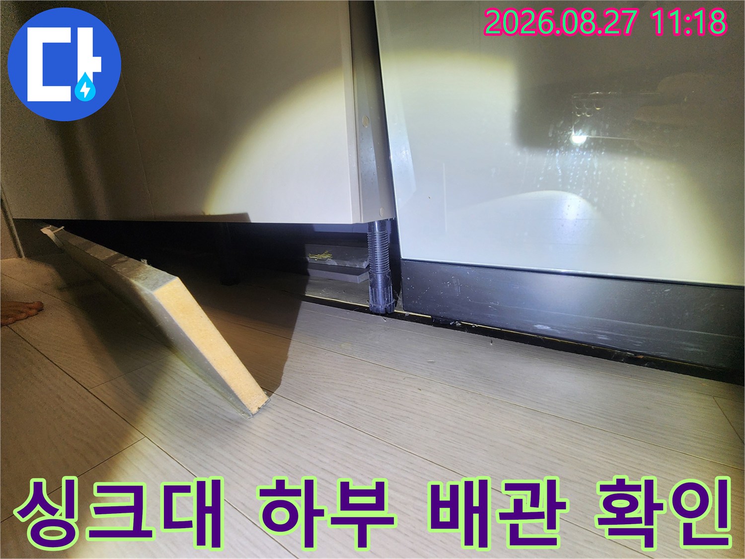 싱크대 하단 마감재가 분리된 누수 점검 현장의 모습입니다.