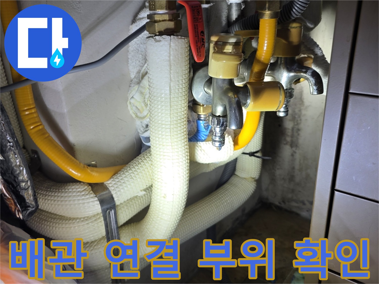 금속 밸브와 노란색 배관이 연결된 싱크대 하단 모습