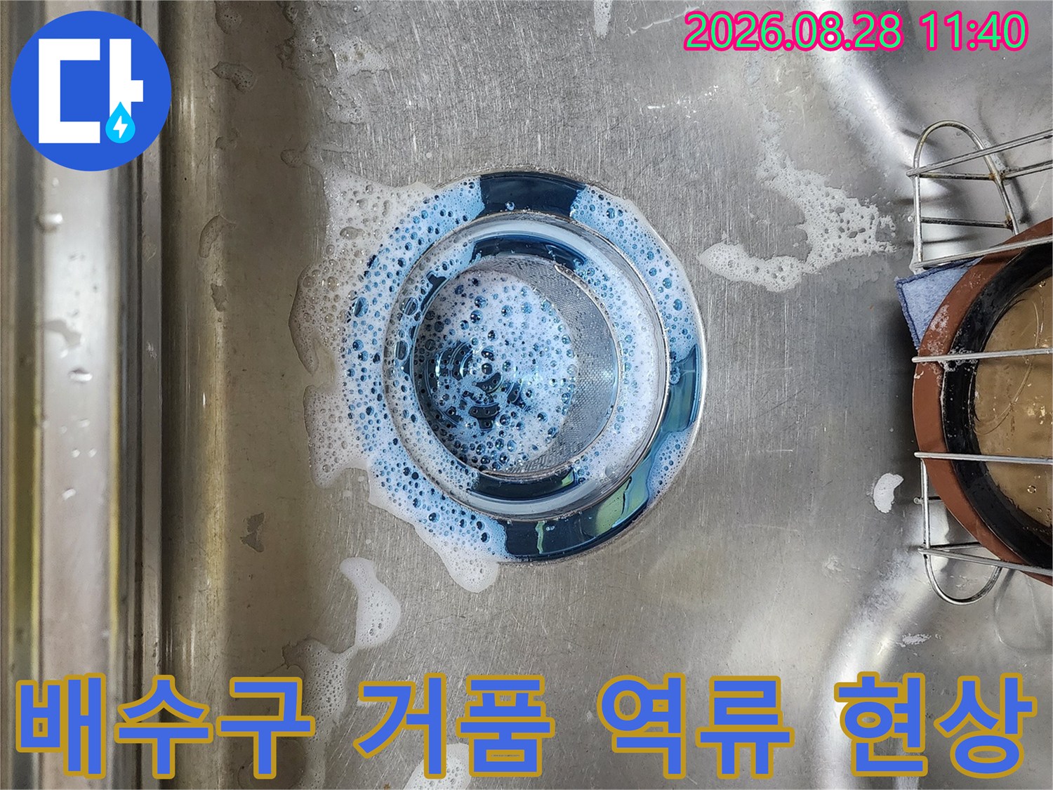 스테인리스 싱크대 배수구에 물과 거품이 차 있는 사진입니다.