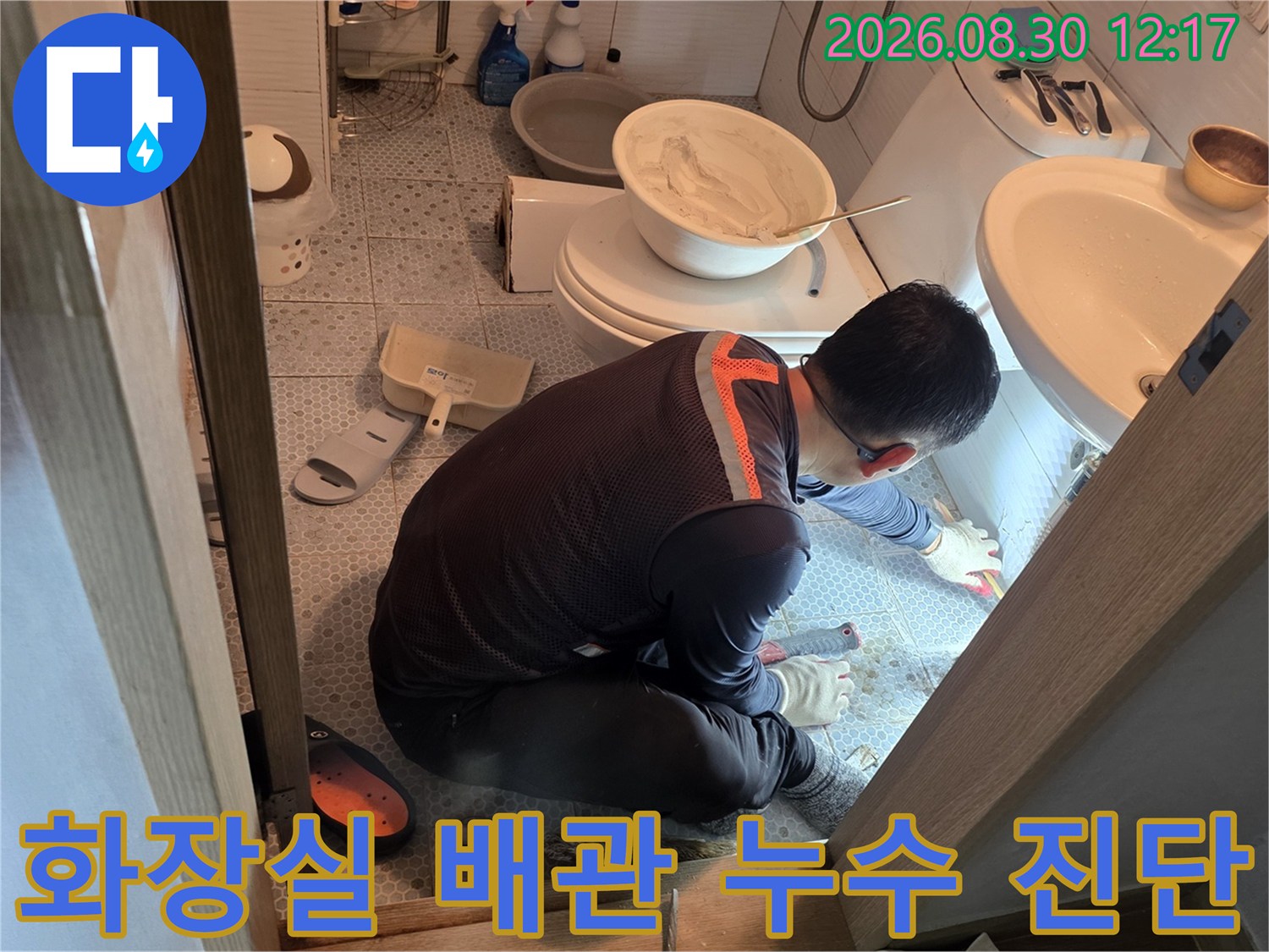 세면대 하부 타일을 제거하고 노출된 배관의 누수 부위를 조사하는 작업 장면