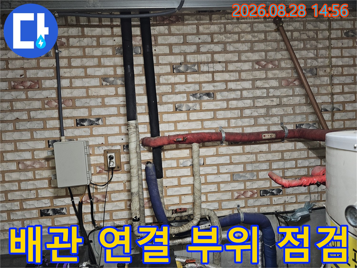 벽돌 벽면의 보온재로 감싸진 배관과 전기 박스 주변 모습입니다.