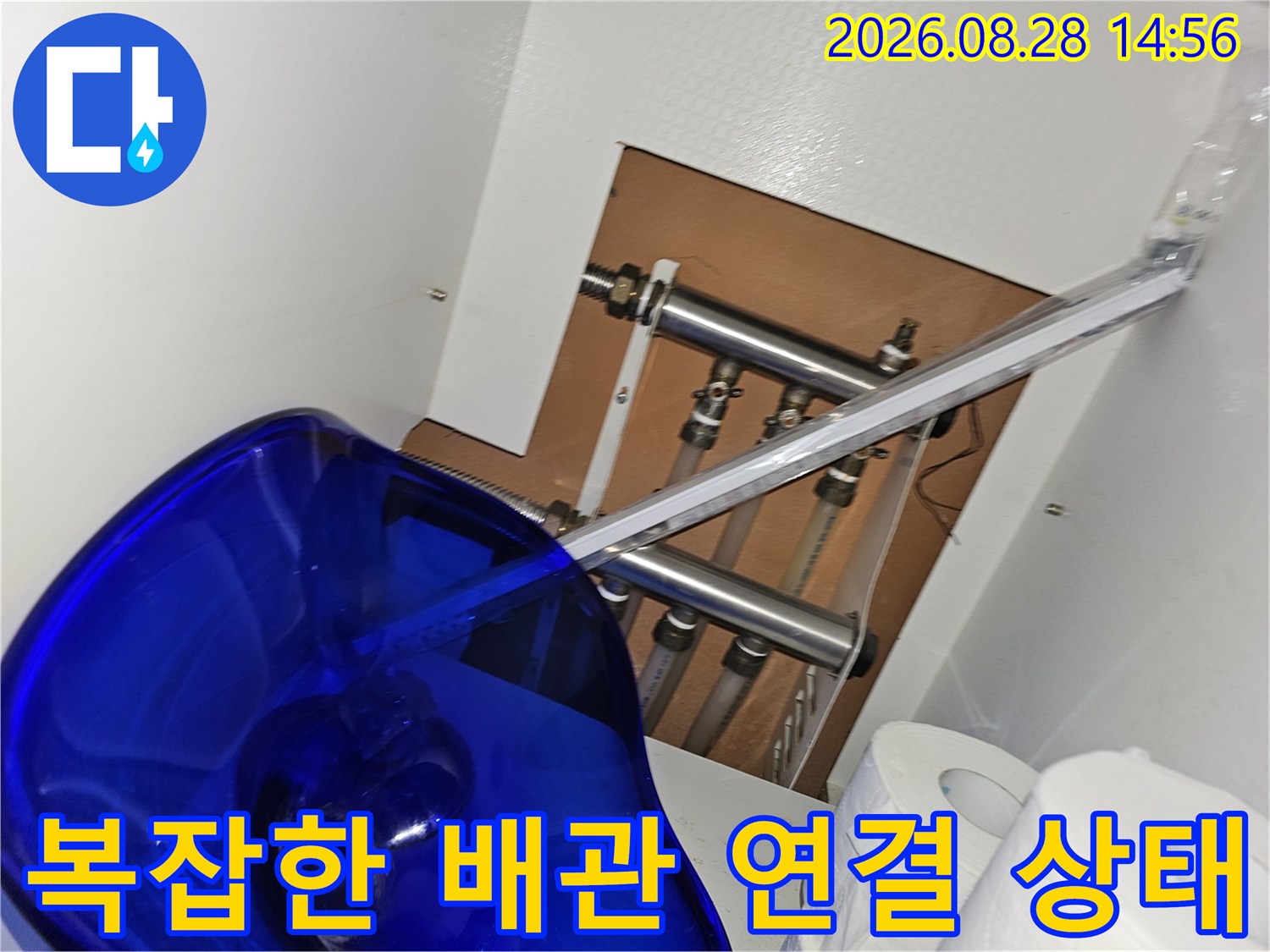 싱크대 하단 공간에 설치된 여러 개의 금속 배관과 연결 부품들의 상세 모습입니다.