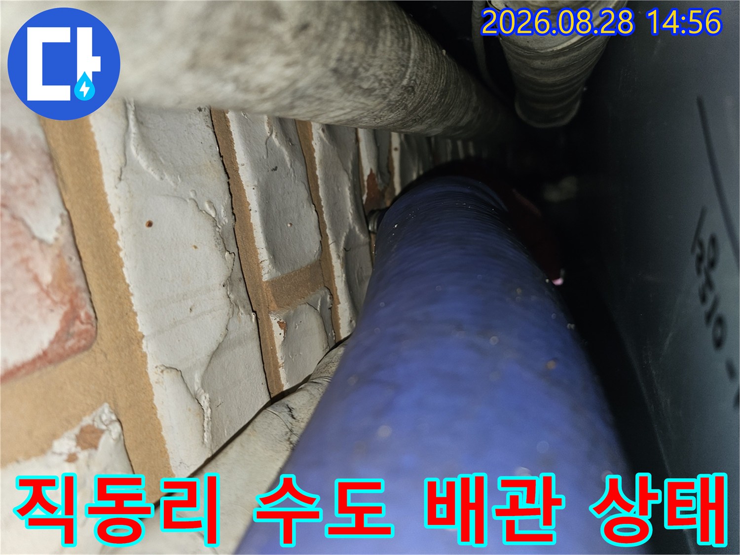 파란색 배관과 흰색 배관이 벽돌 구조물 근처에 설치된 모습