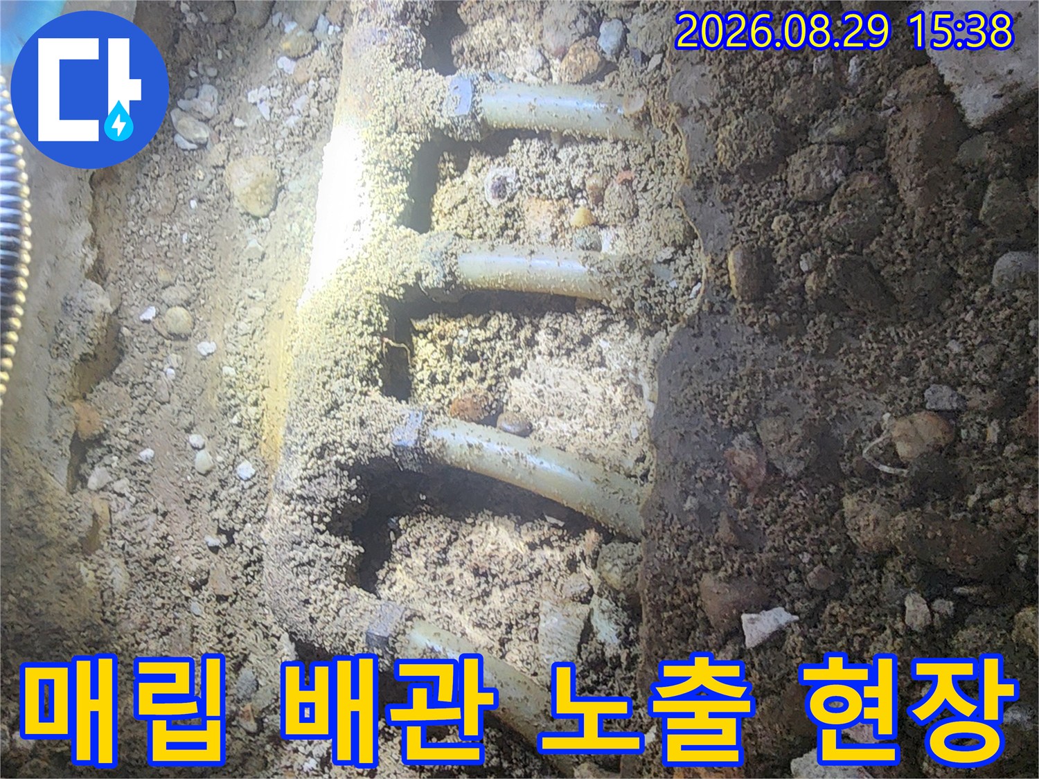 싱크대 아래 흙과 자갈 속에 드러난 여러 갈래의 배관들