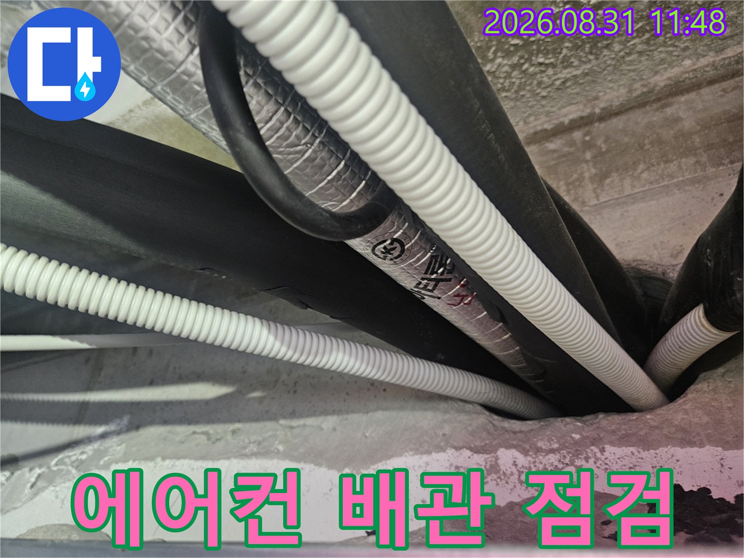 천장 내부의-하얀색 주름관과 검은색 보온재 배관 모습입니다.