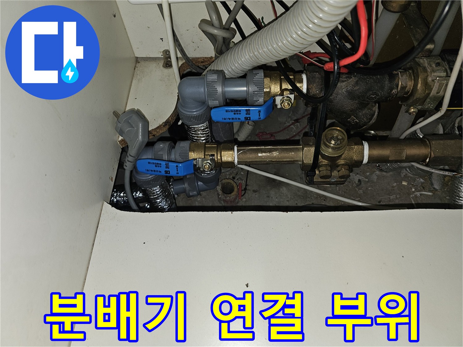 난방 분배기에 연결된 파란색 밸브와 금속 관들의 복잡한 구조