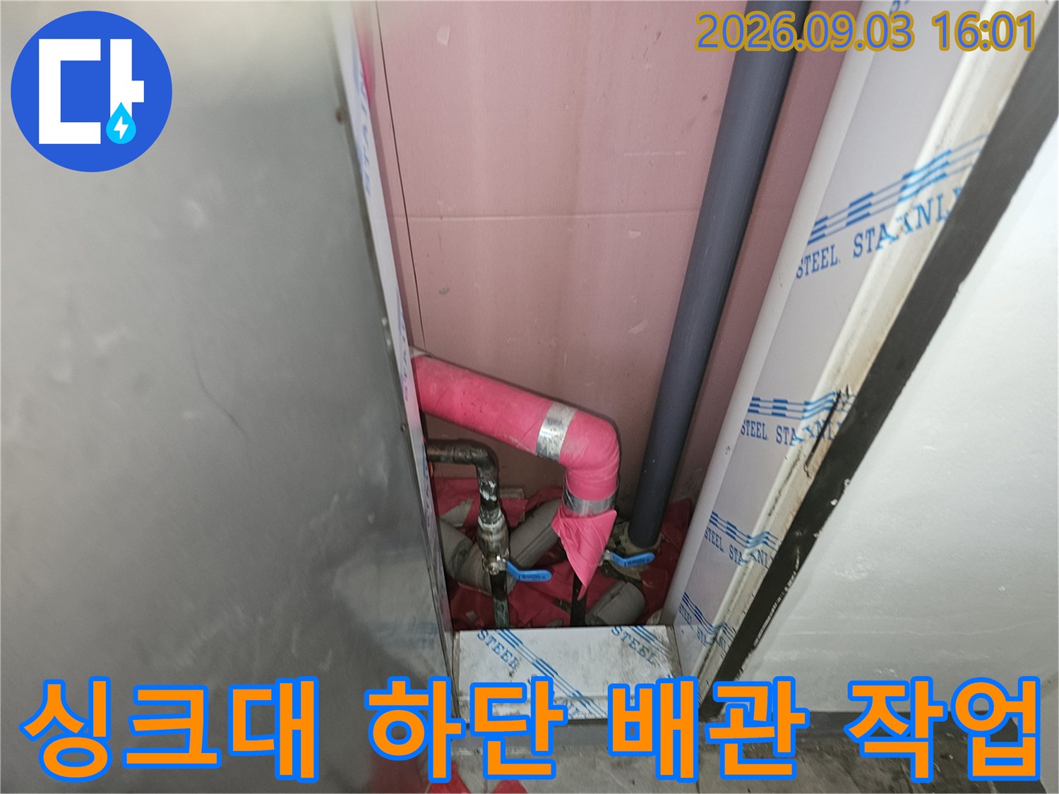 싱크대 하단 공간에 설치된 분홍색 단열 배관과 회색 배관
