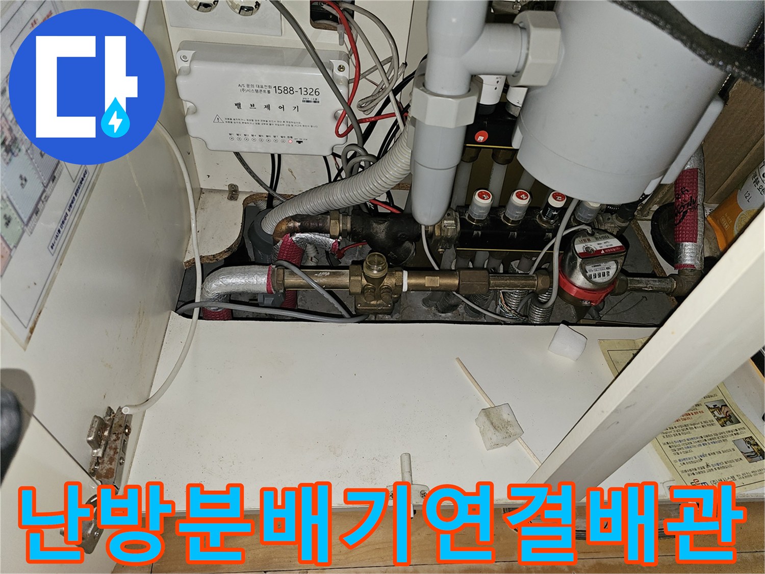 싱크대 하부장 내부에 설치된 난방 분배기와 금속 재질의 배관들입니다.