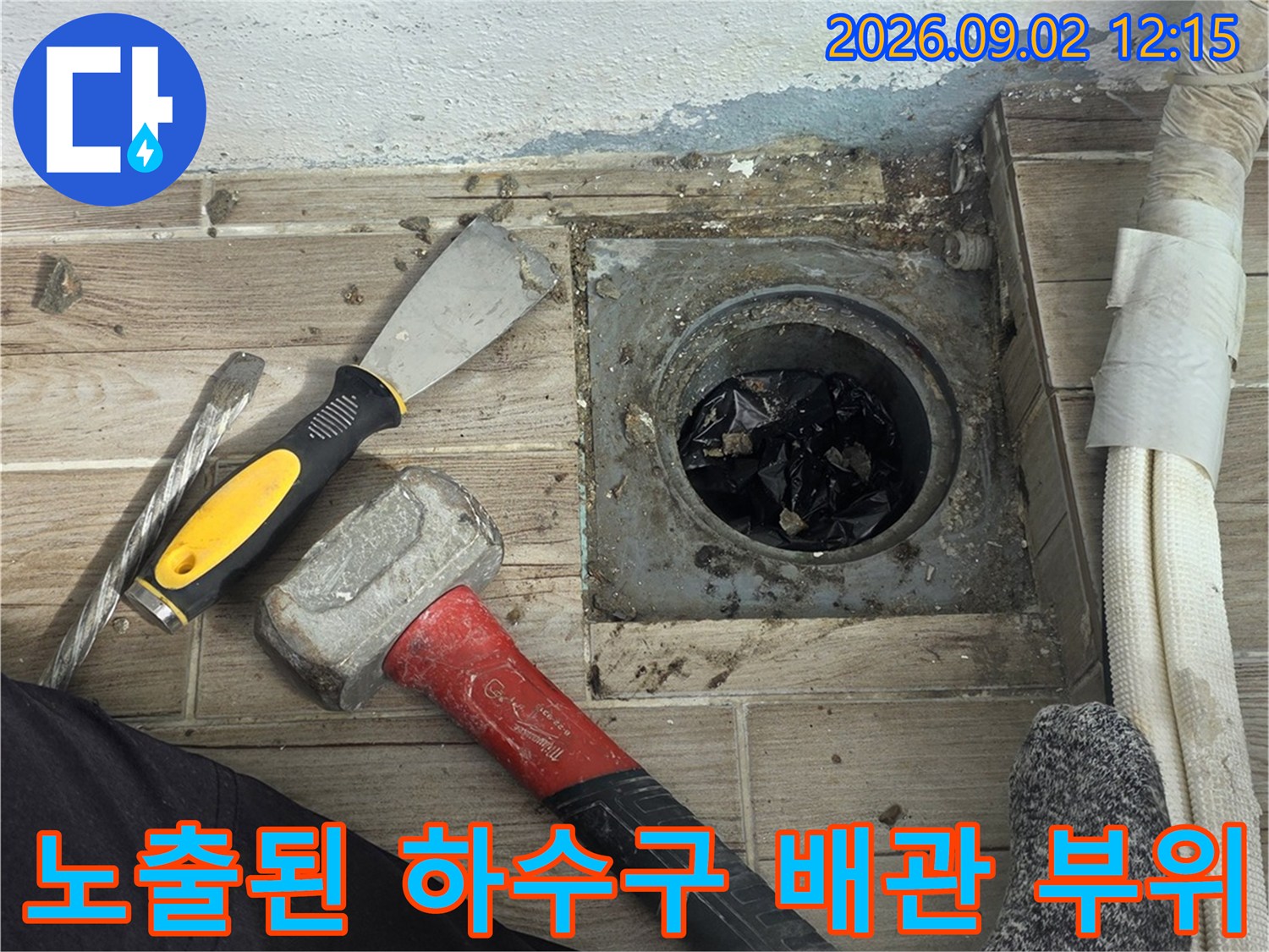 타일 아래 드러난 배관과 작업용 공구들의 모습