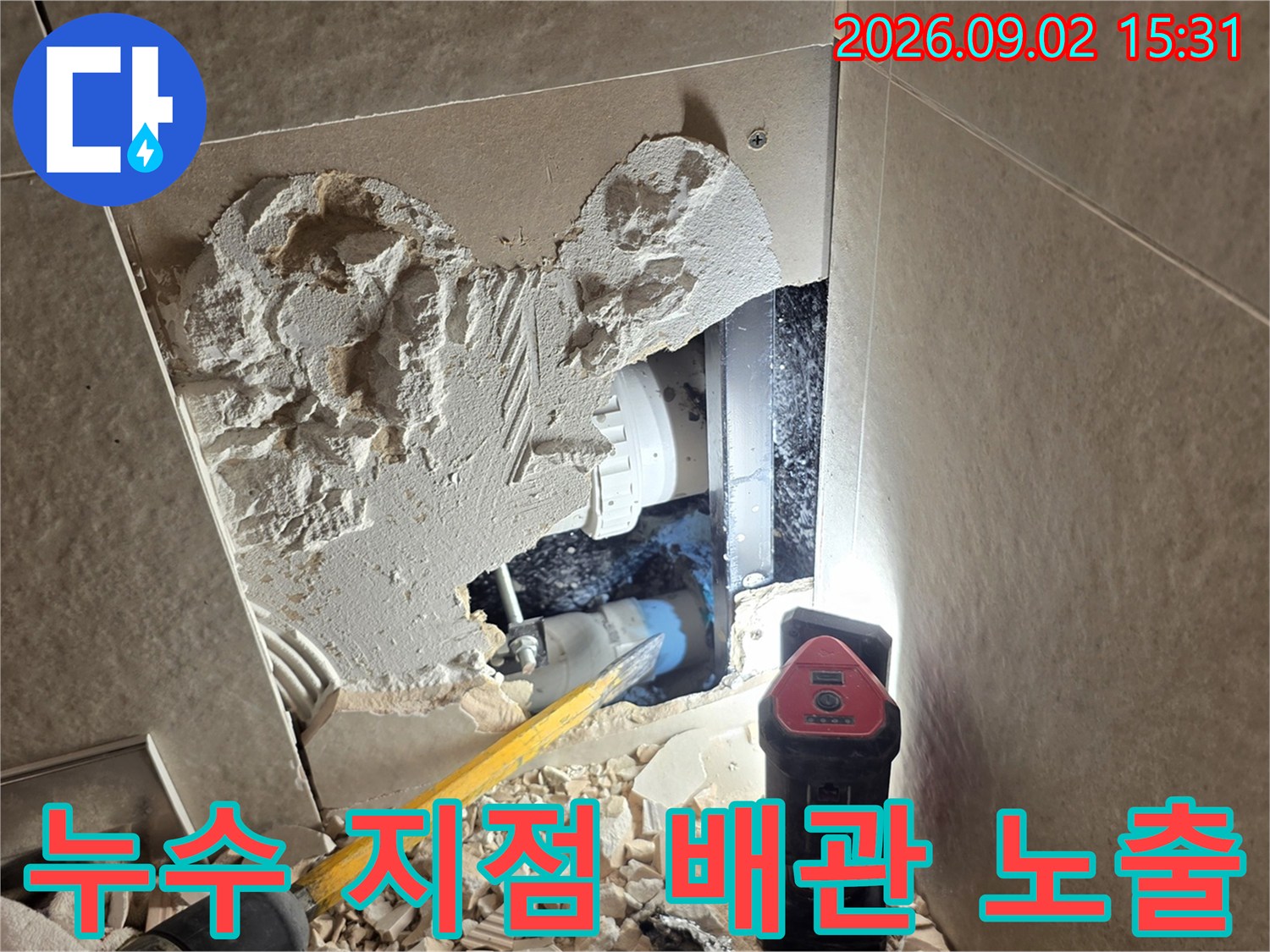 벽면 굴착 부위 내부에 노출된 파손된 배관과 작업용 조명