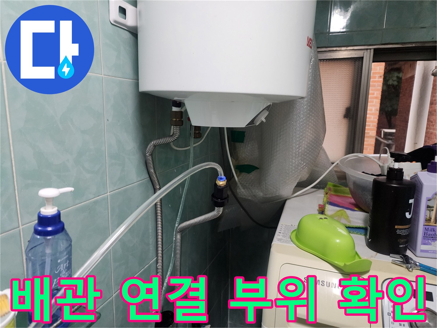 벽면에 노출된 수도 배관과 정수기 호스의 연결 상태를 점검하는 장면입니다.