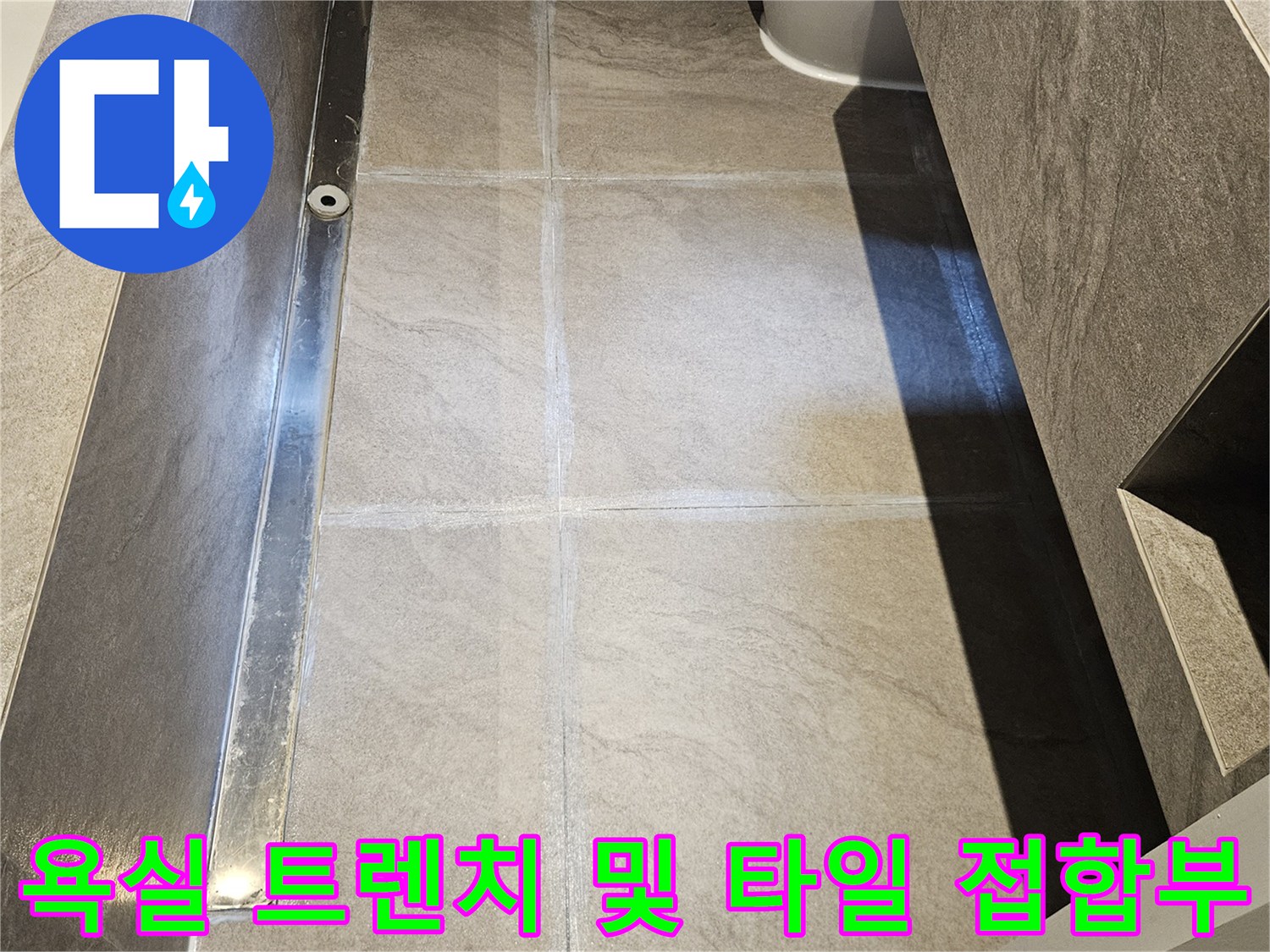 대리석 느낌의 욕실 바닥재와 스테인리스 트렌치 배수구 근접 사진