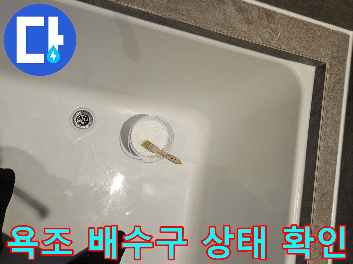 하얀색 욕조 내부의 배수구와 점검용 도구가 놓여 있는 모습입니다.