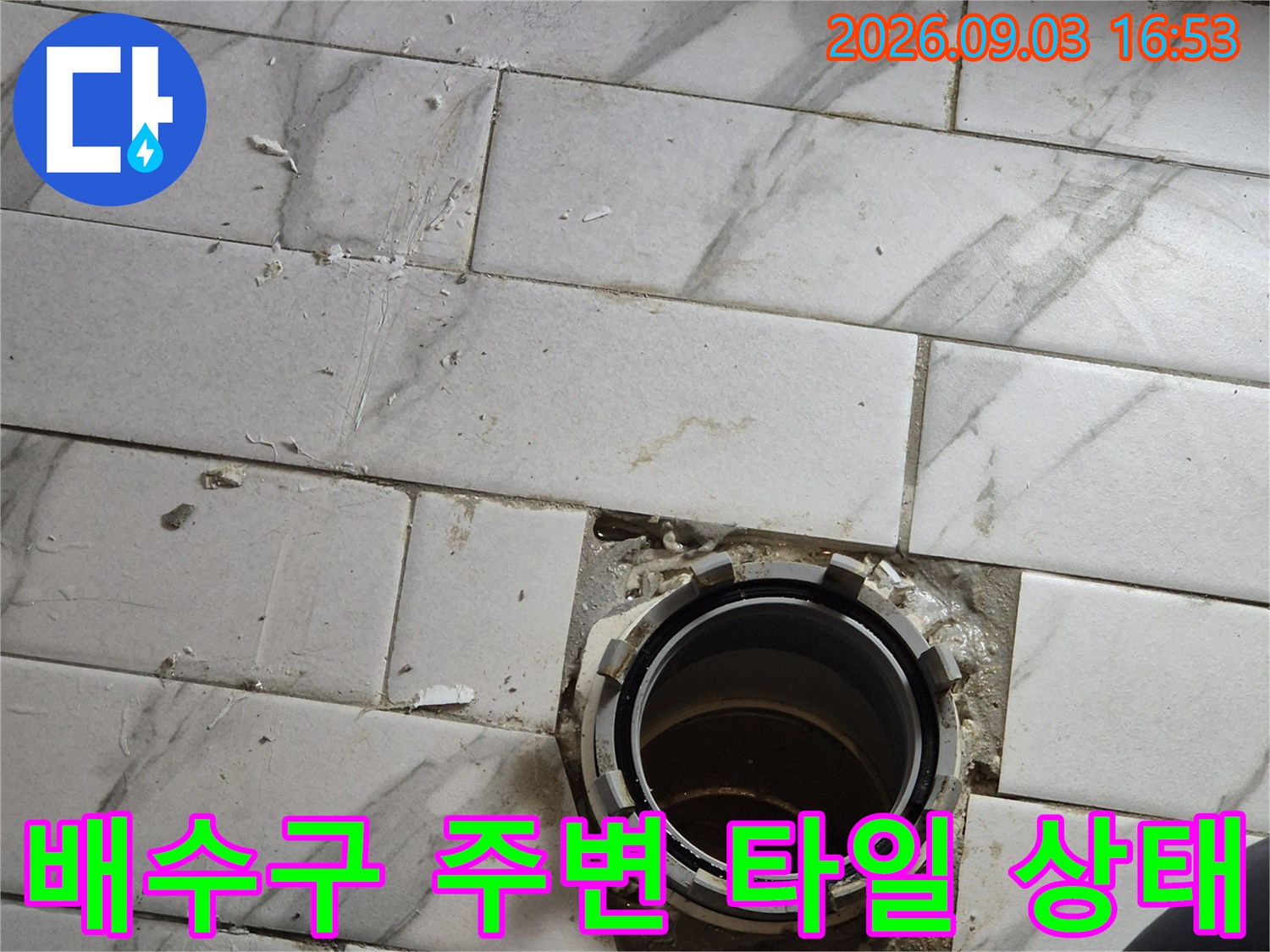 배수구 배관과 주변 타일의 틈새를 정밀하게 관찰하고 있습니다.