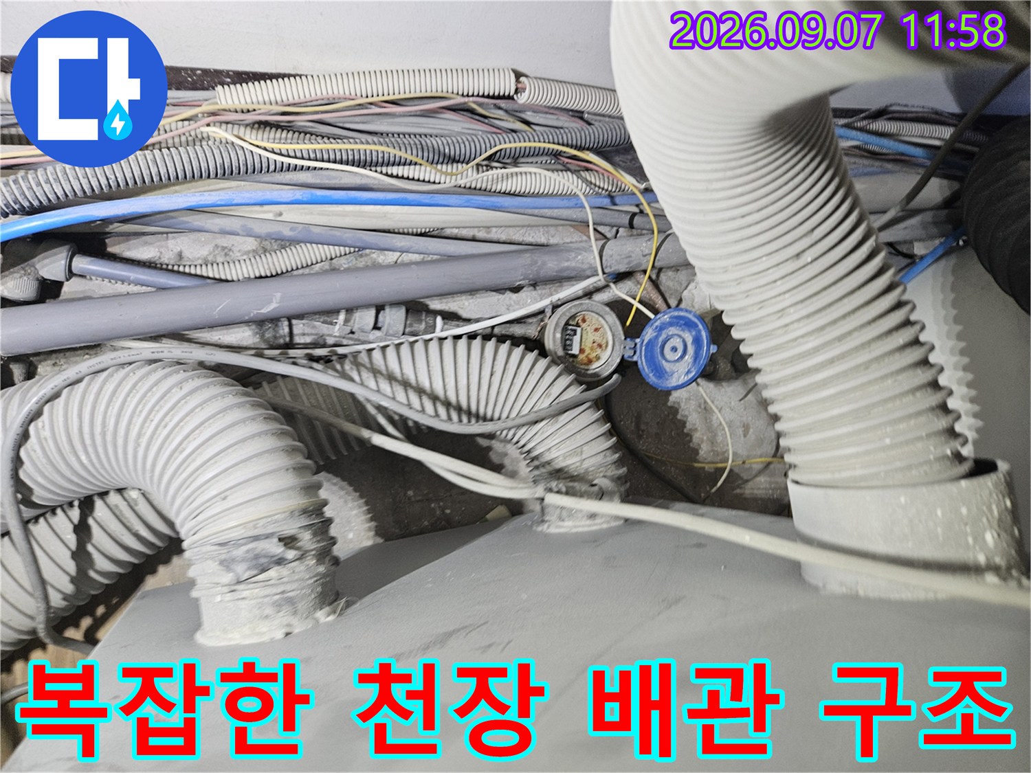 굴곡진 자바라 배관과 전기 콘센트가 있는 천장 내부