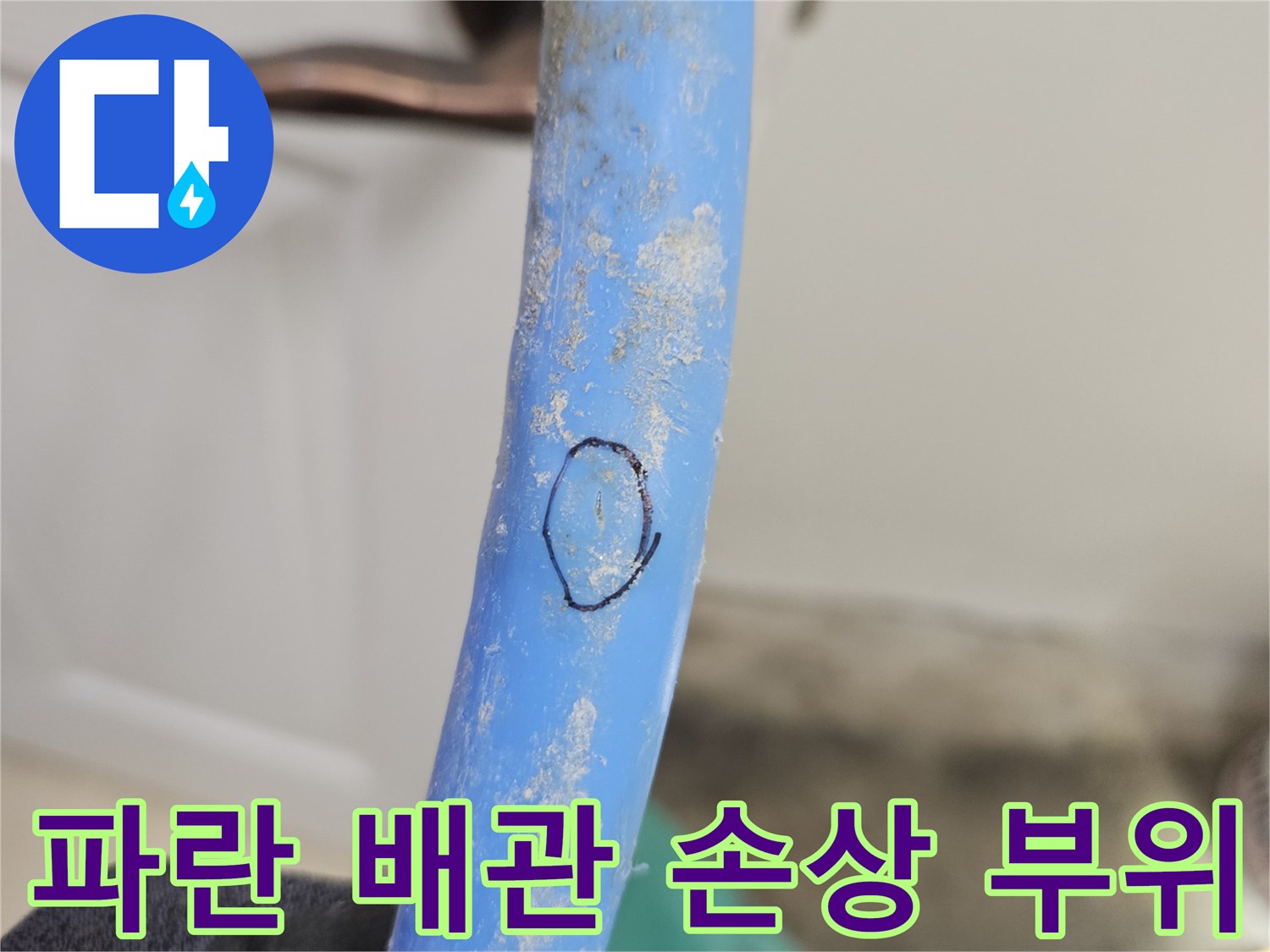 손으로 잡고 있는 파란색 배관의 하얀 얼룩과 긁힌 흔적
