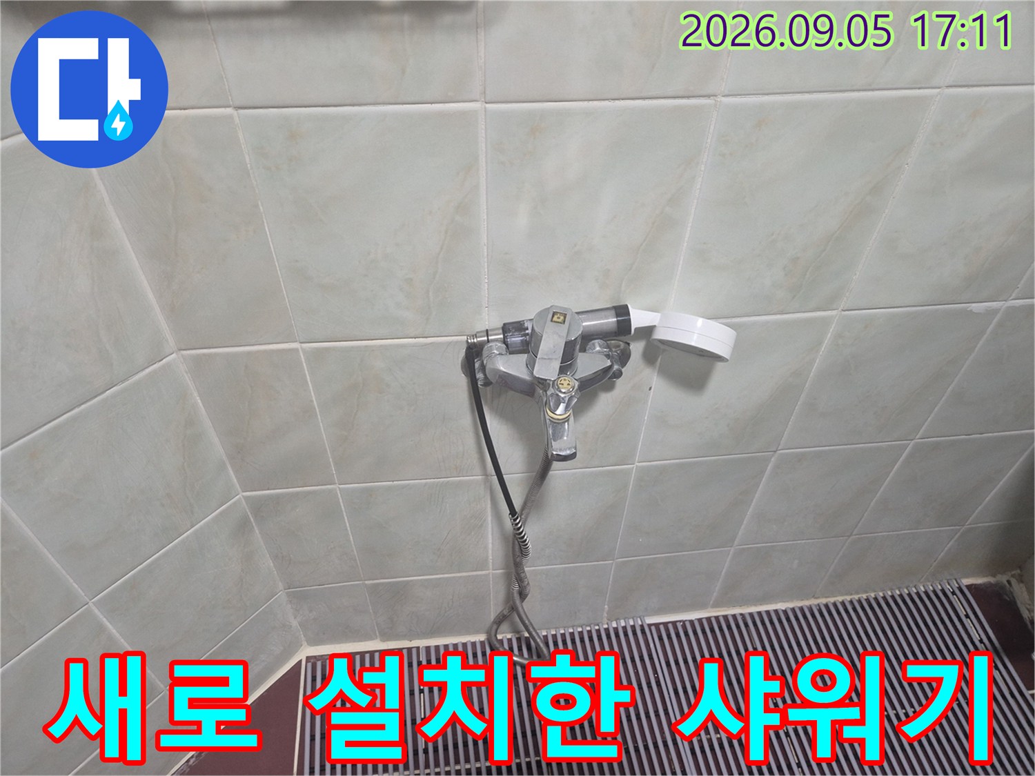 벽면 타일 사이에 견고하게 고정된 샤워 수전과 호스 연결 상태입니다.