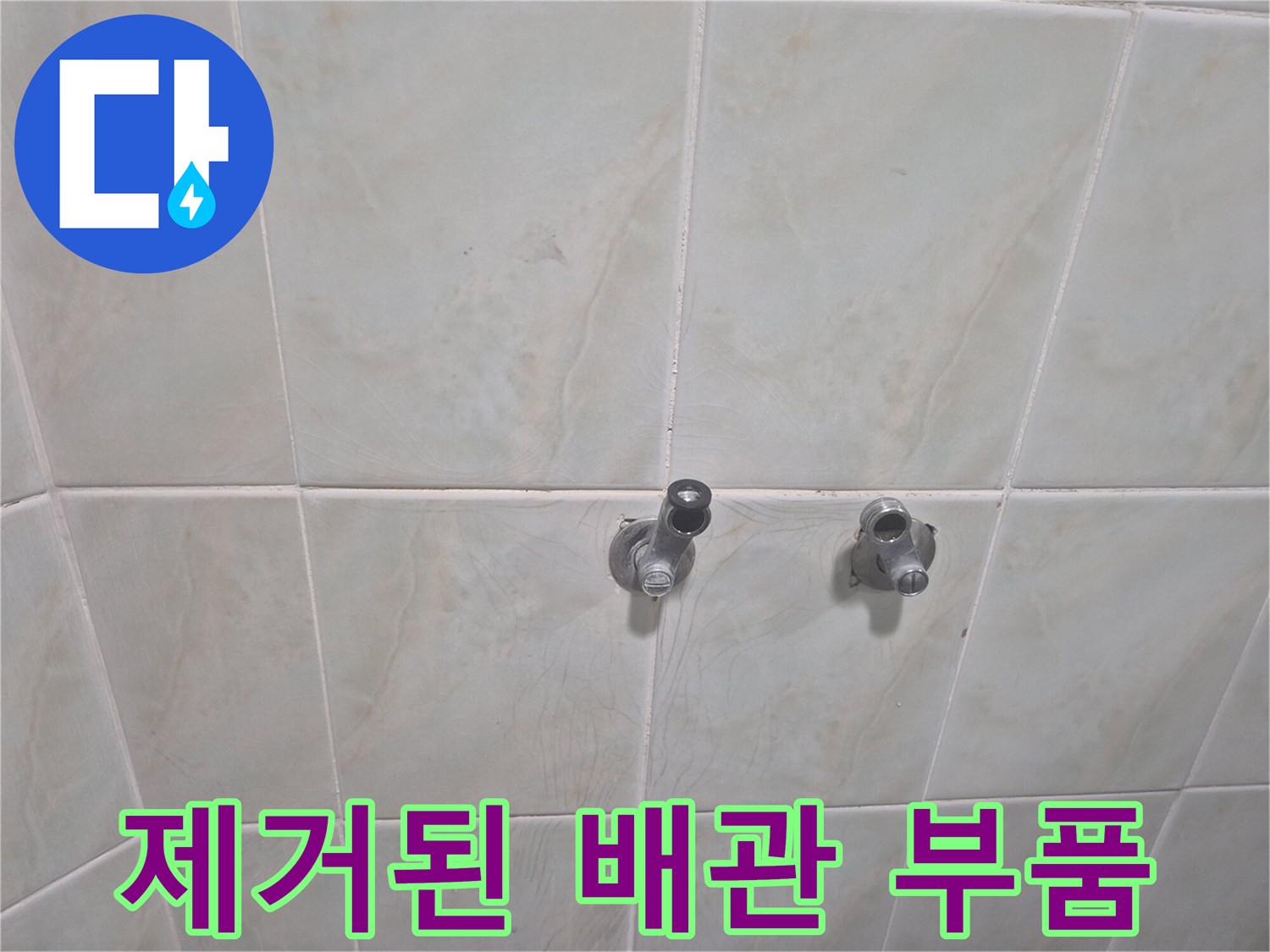샤워기 수전을 분리하여 벽면 배관이 드러난 화장실 내부 사진입니다.