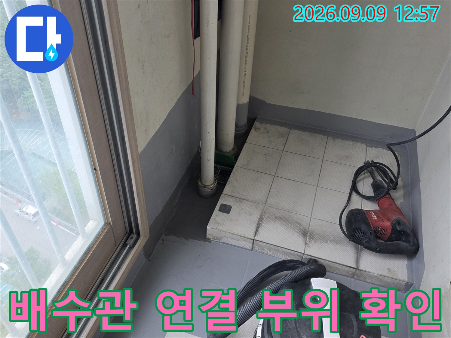 배수관 주변의 젖은 타일과 작업용 전동 공구