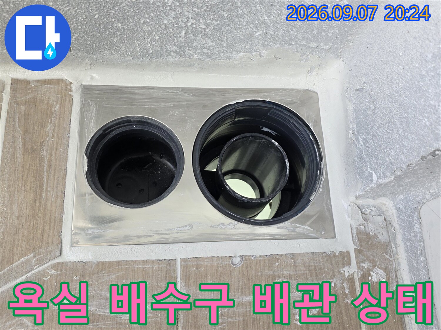 동해시 욕실 배수구 주변의 노출된 배관과 타일 마감 상태를 보여주는 사진입니다.
