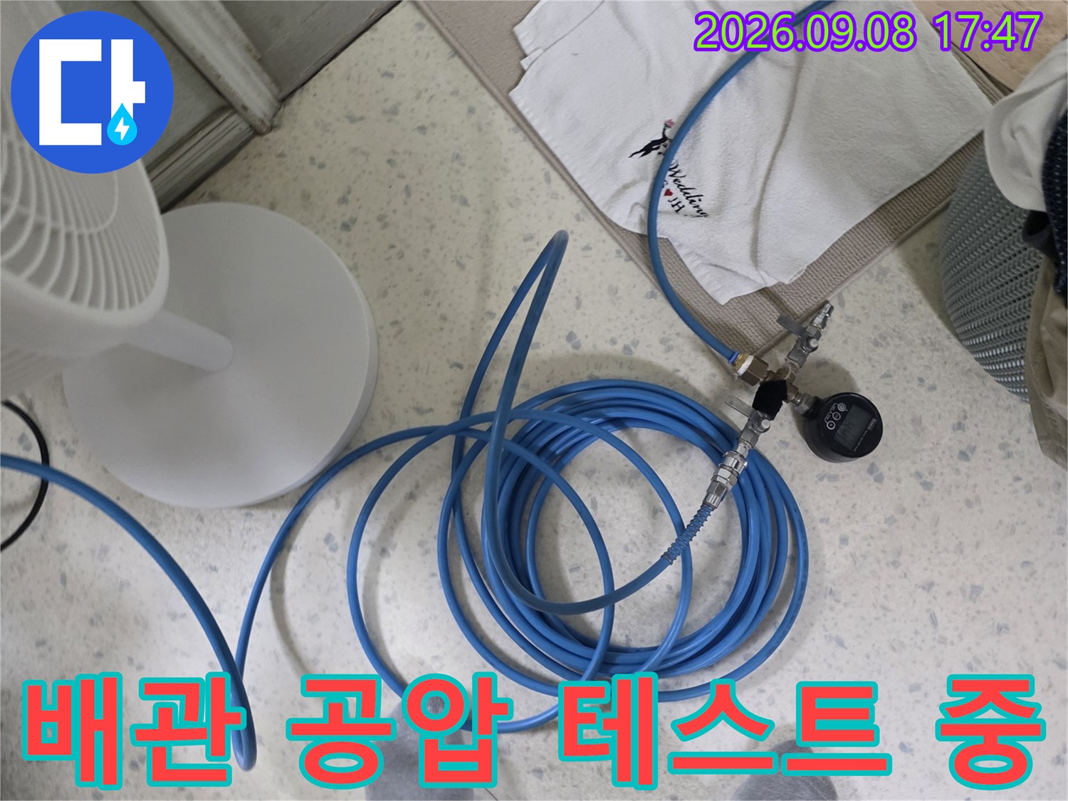 파란색 호스가 연결된 압력 측정 장비와 작업 현장 바닥