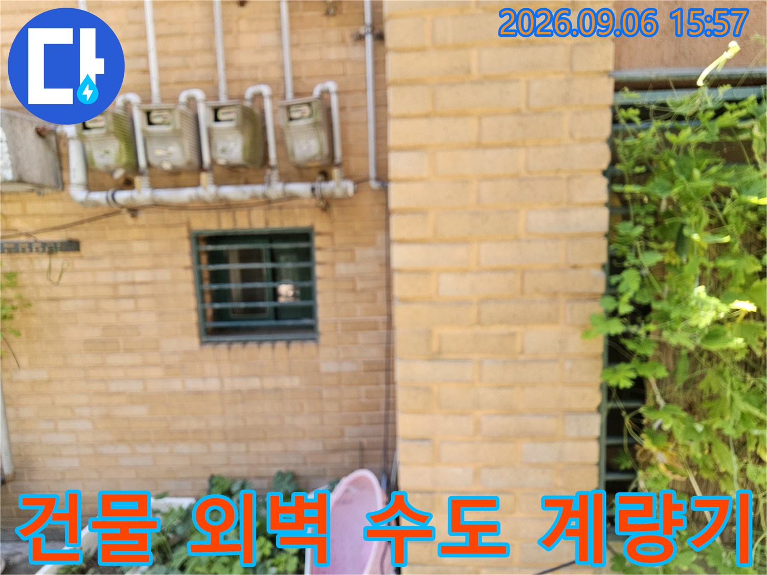 벽돌 벽에 설치된 여러 개의 수도 계량기와 연결 배관입니다.