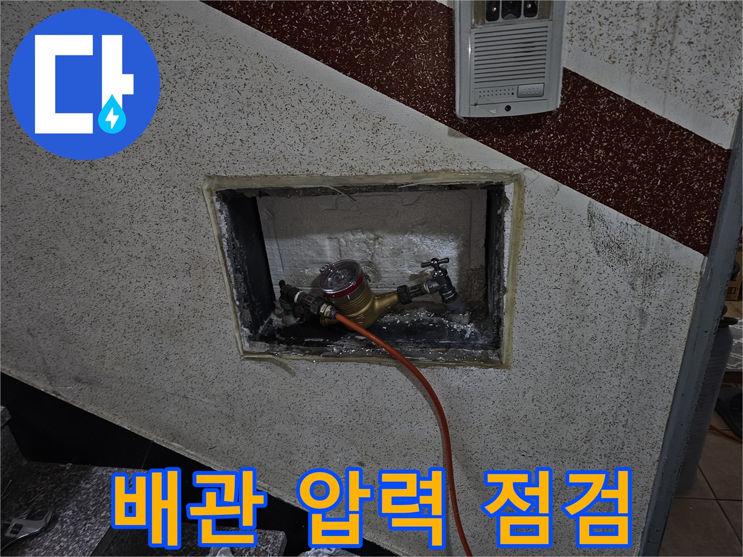 벽면 타공 공간 내부에 보이는 계량기와 연결된 압력 테스트 호스