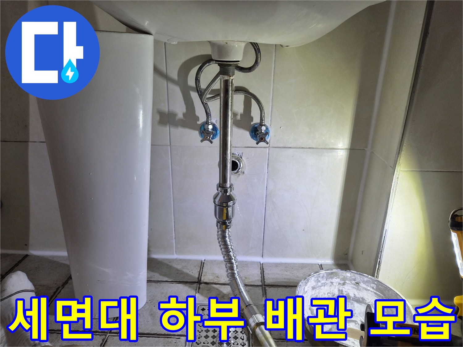 벽면에 설치된 세면대 배수 호스와 타일 벽면 상세