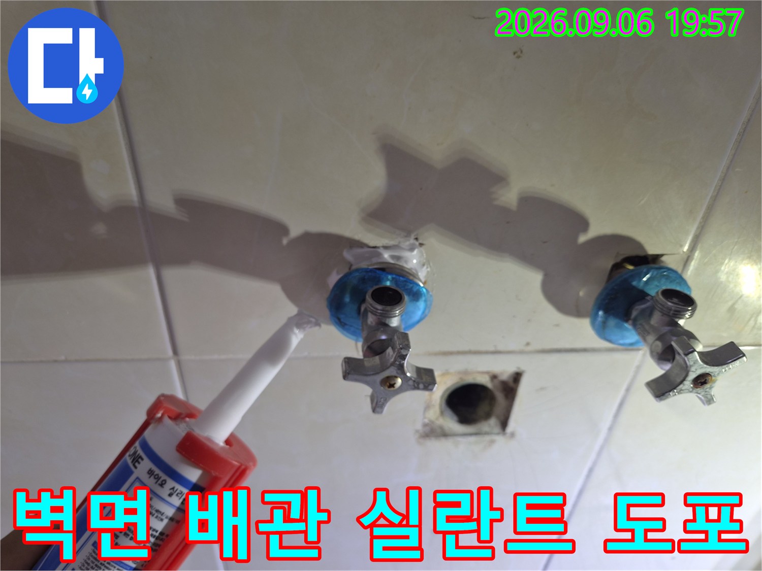 하얀색 실란트를 사용하여 벽면 수전 배관의 틈새를 메우는 작업 장면입니다.