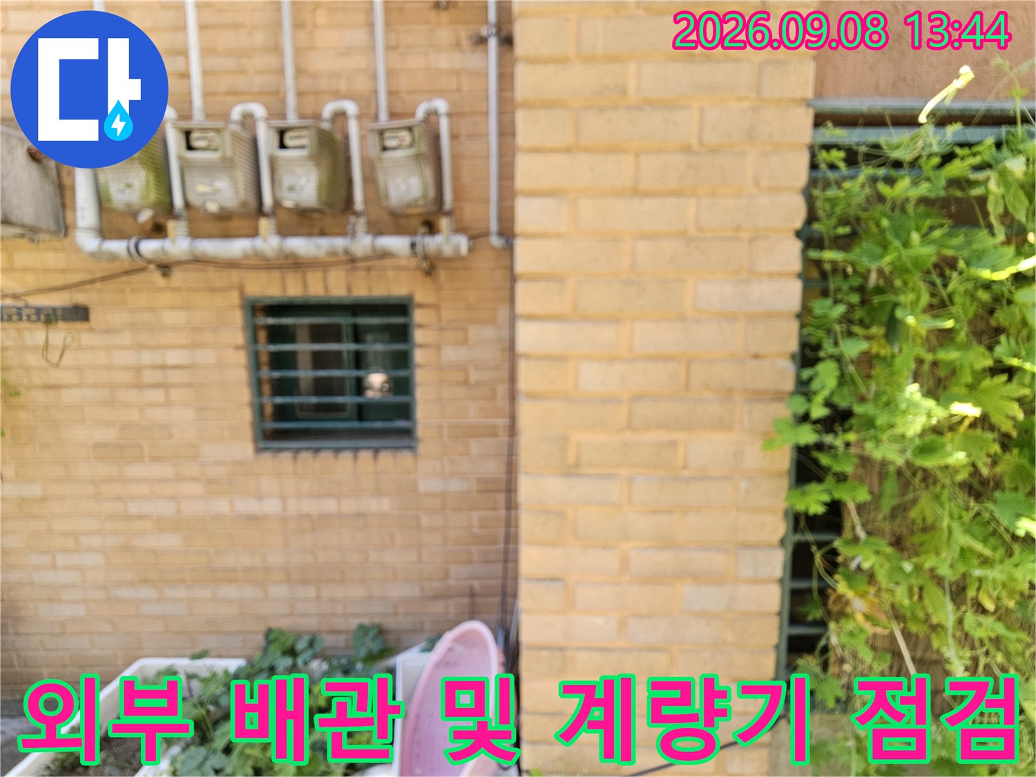 벽돌 벽면에 설치된 수도 계량기와 연결된 배관 구조-누수 진단 중