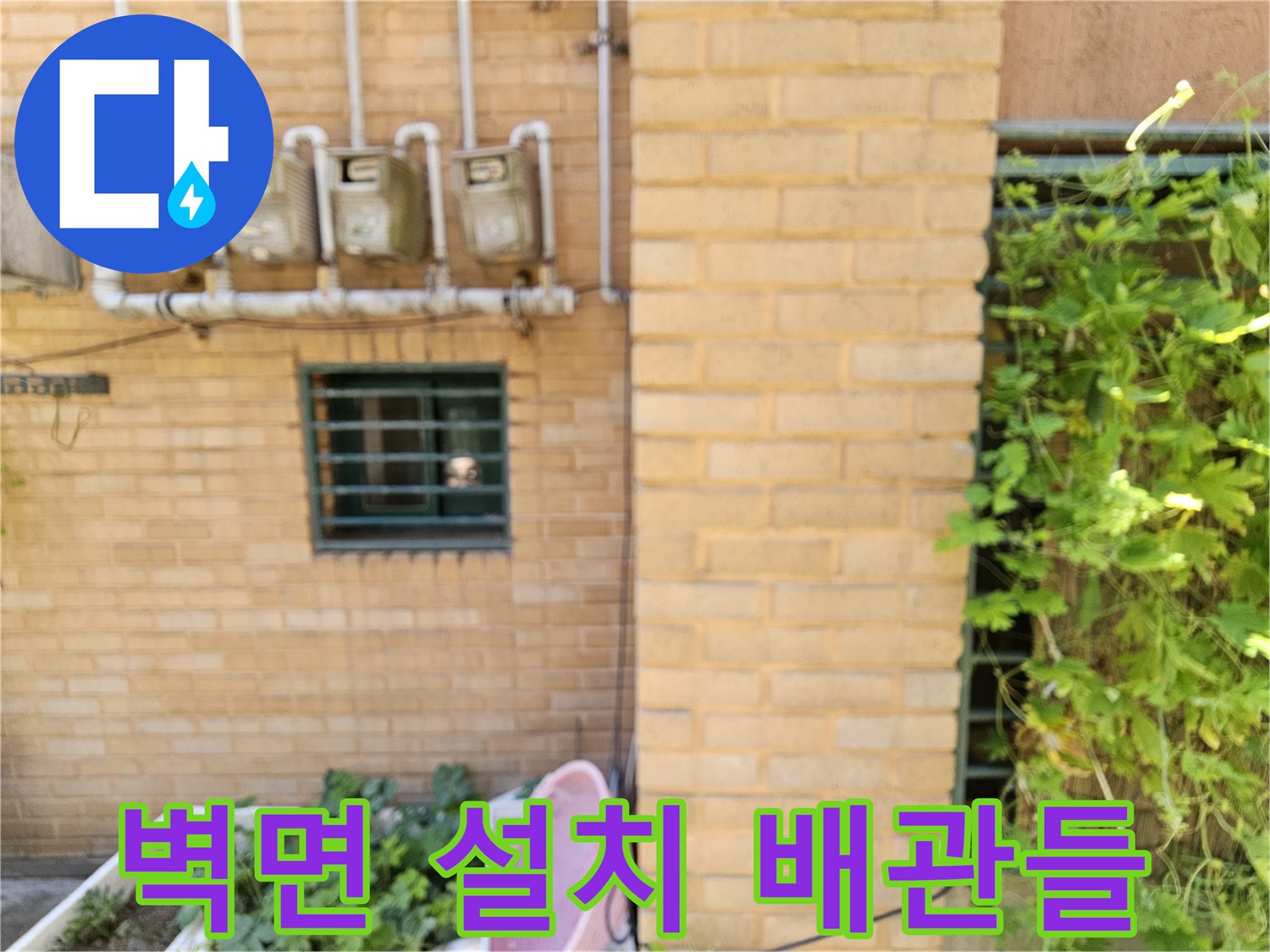 황색 벽돌 건물 외벽에 일렬로 배치된 수도 계량기와 급수 파이프