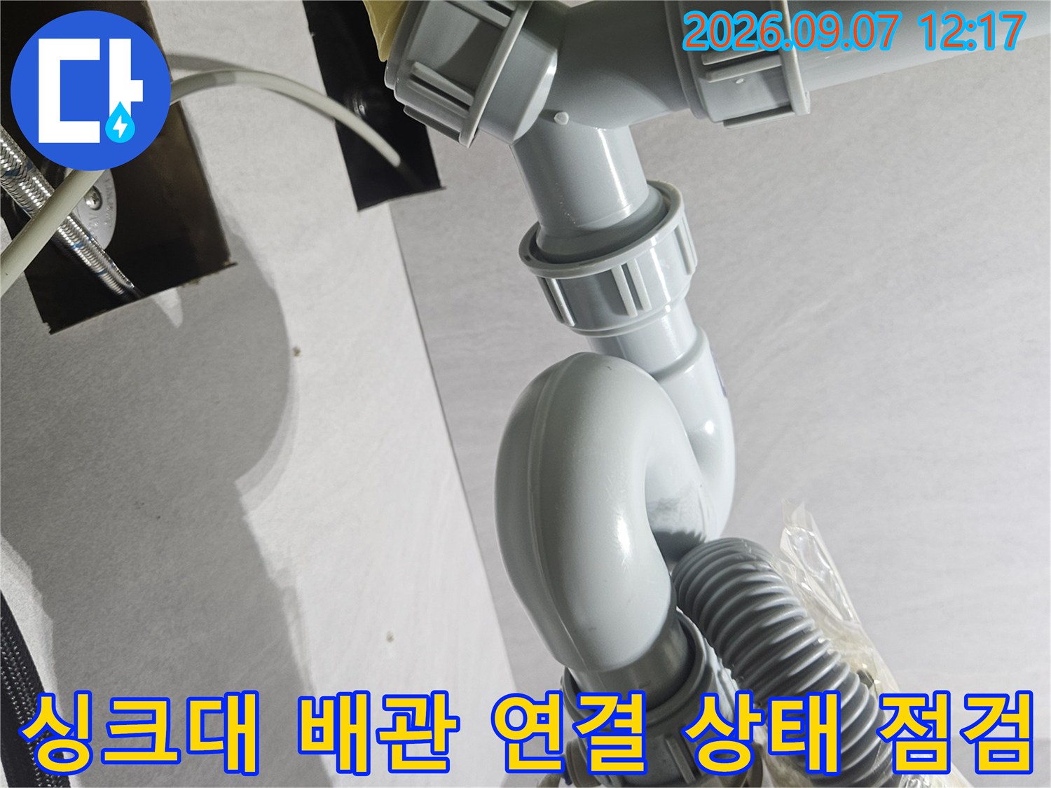 싱크대 하단에 위치한 굴곡진 배수관과 호스들의 결합 상태입니다