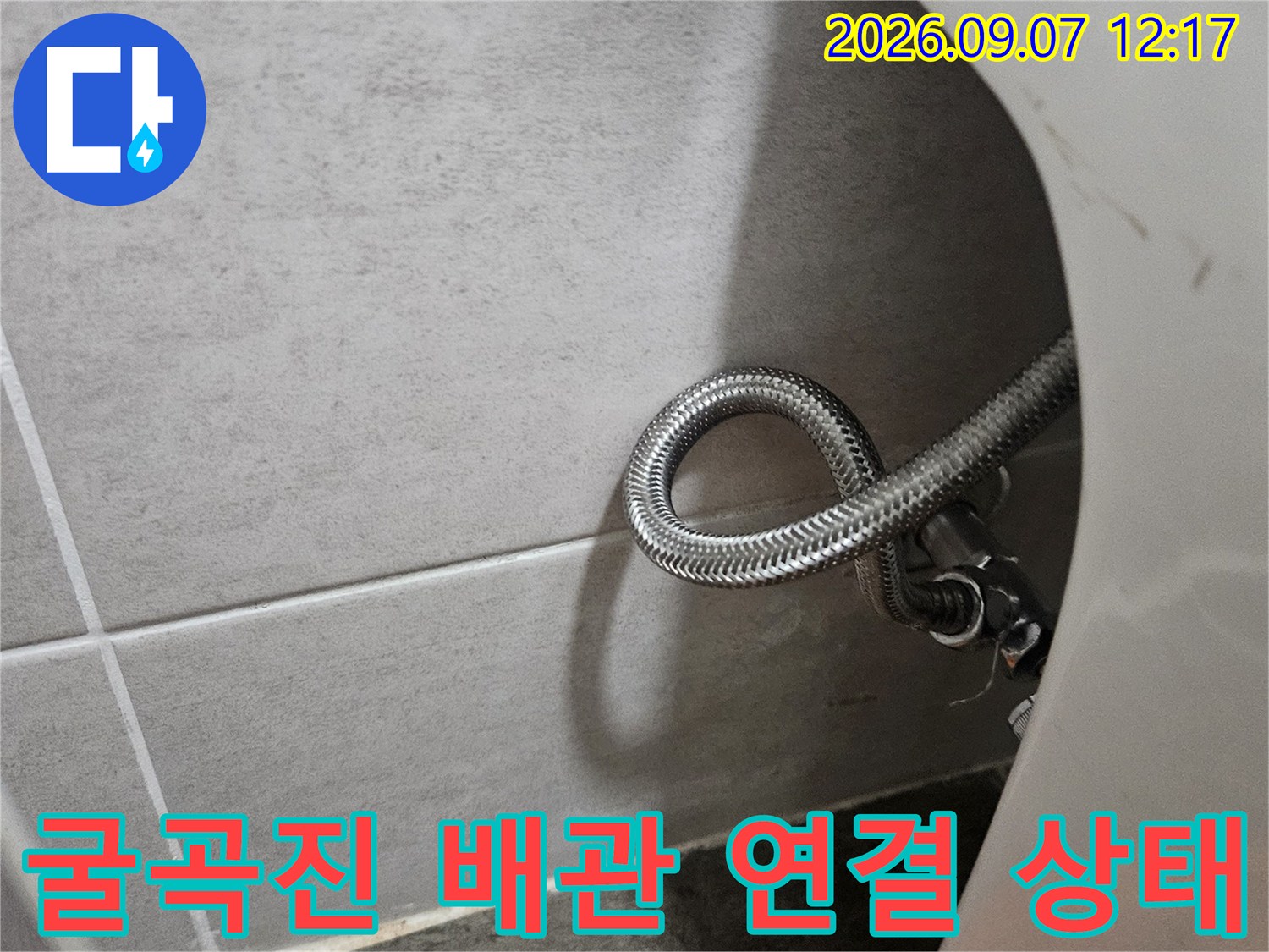 은색 스테인섭리스 호스가 둥글게 말려 있는 싱크대 하부 모습