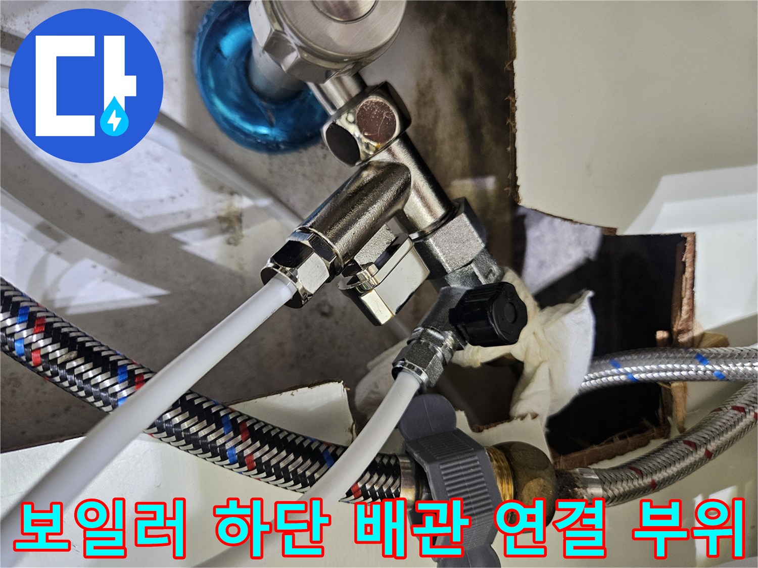 보일러 아래쪽 금속 밸브와 흰색 배관이 만나는 지점의 근접 사진