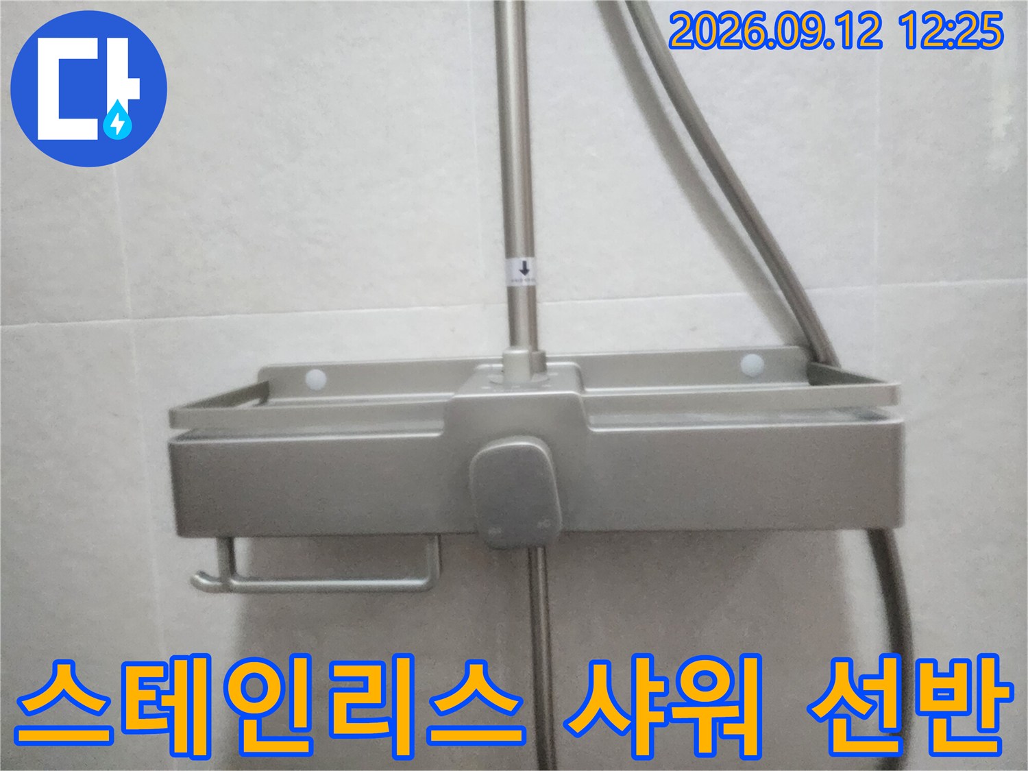 욕실 벽면에 설치된 스테인리스 소재의 샤워기용 수납 선반 사진입니다.