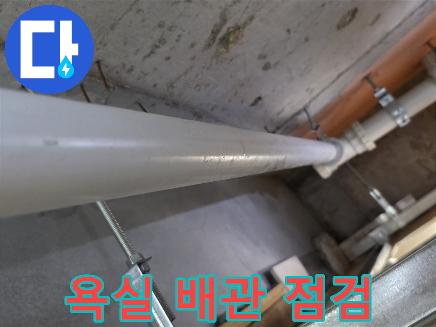 아래층 욕실 천장에 설치된 하얀색 PVC 배관과 고정용 브라켓 모습