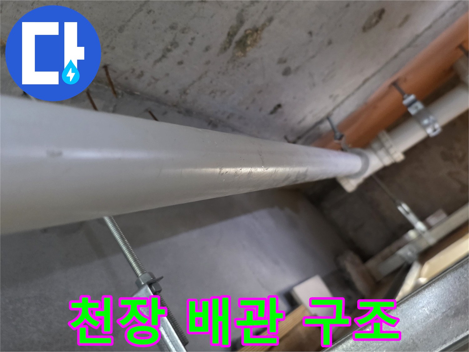 콘크리트 천장에 고정된 흰색 PVC 배수 파이프와 지지대