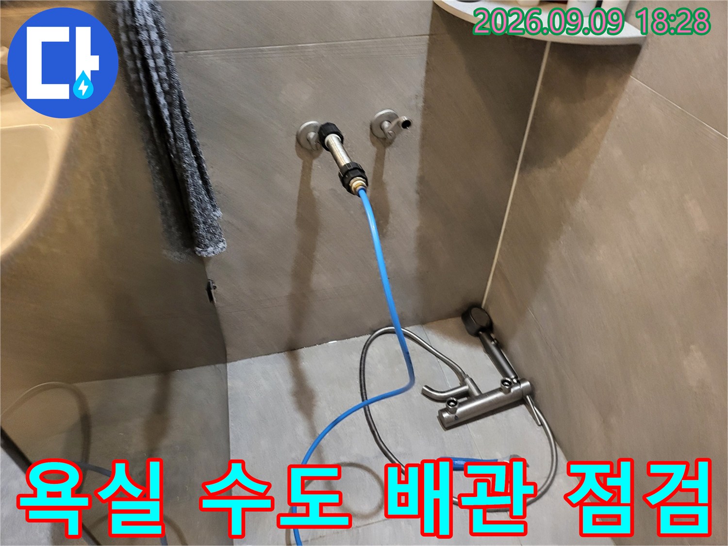 벽면 수전 배관에 파란색 호스를 연결하여 누수 여부를 진단하는 장면입니다.