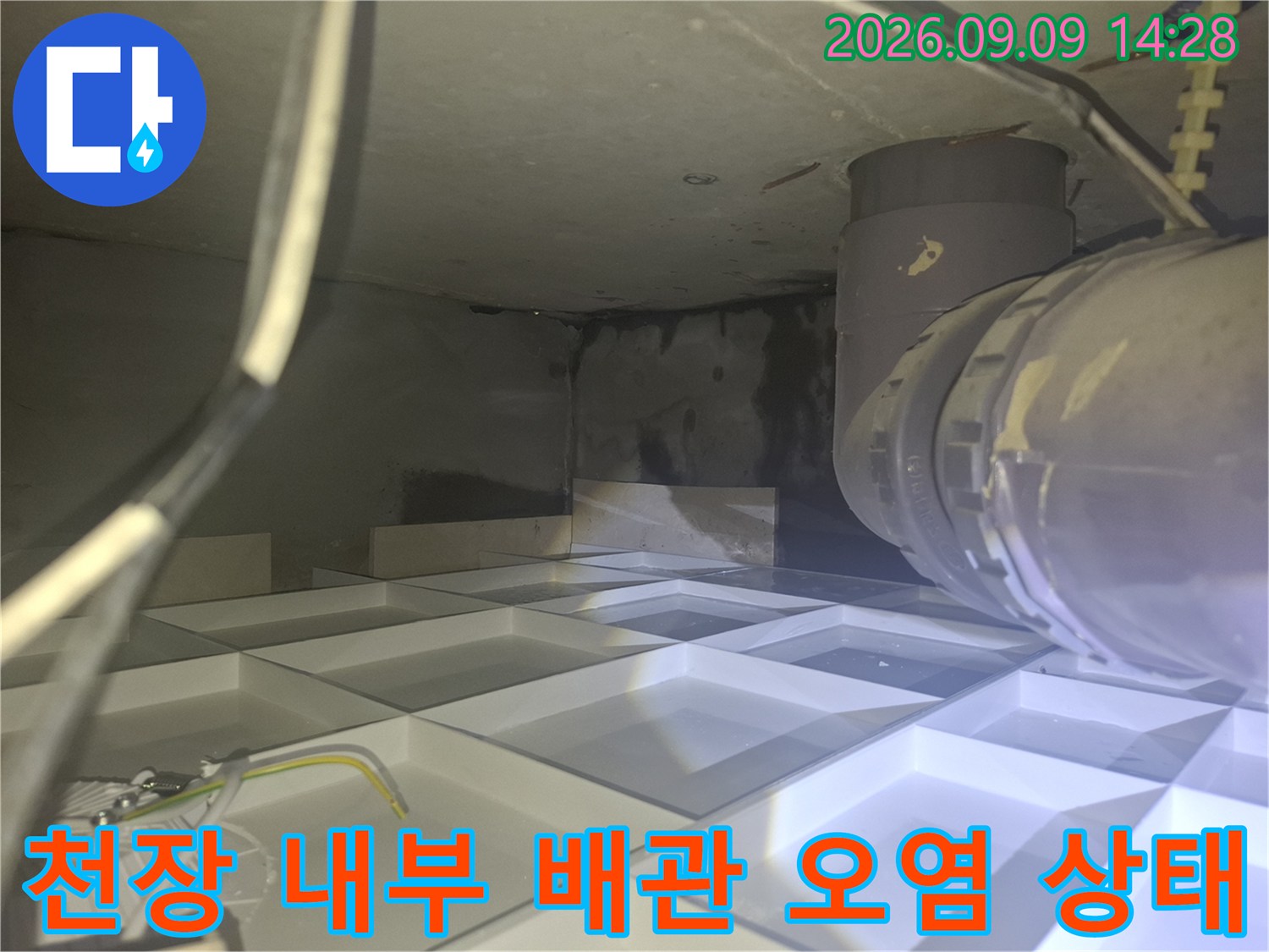 배관 주변에 발생한 어두운 얼룩과 습기를 확인하는 현장 사진입니다.