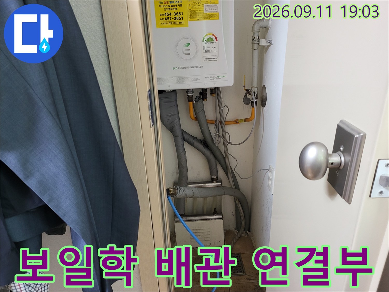 보일러 하단에 연결된 여러 갈래의 배관들과 유연한 호스들의 모습입니다.