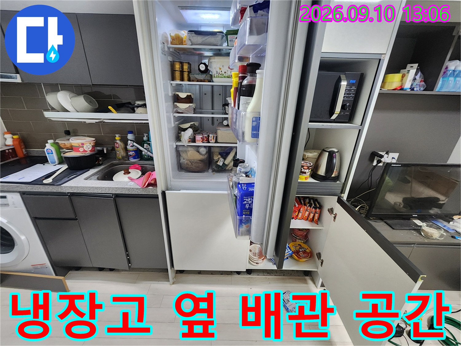 냉장고와 싱크대가 인접한 주방 하부 구조물의 배관 점검 모습
