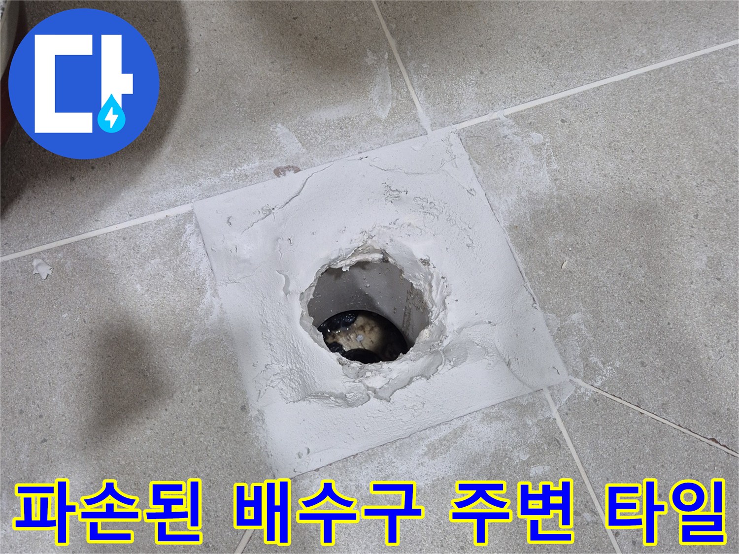 화장실 배수구 주변의 훼손된 타일과 노출된 배관 입구