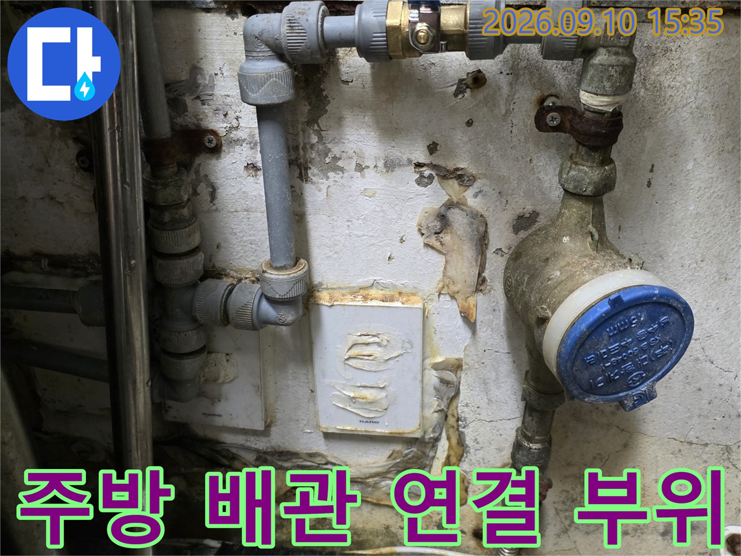 주방 싱크대 근처 수도 계량기와 파란색 밸브가 설치된 배관 모습