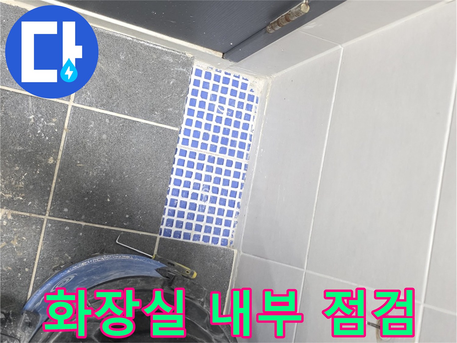 파란색 타일과 작업용 청소 장비가 놓인 화장실입니다.