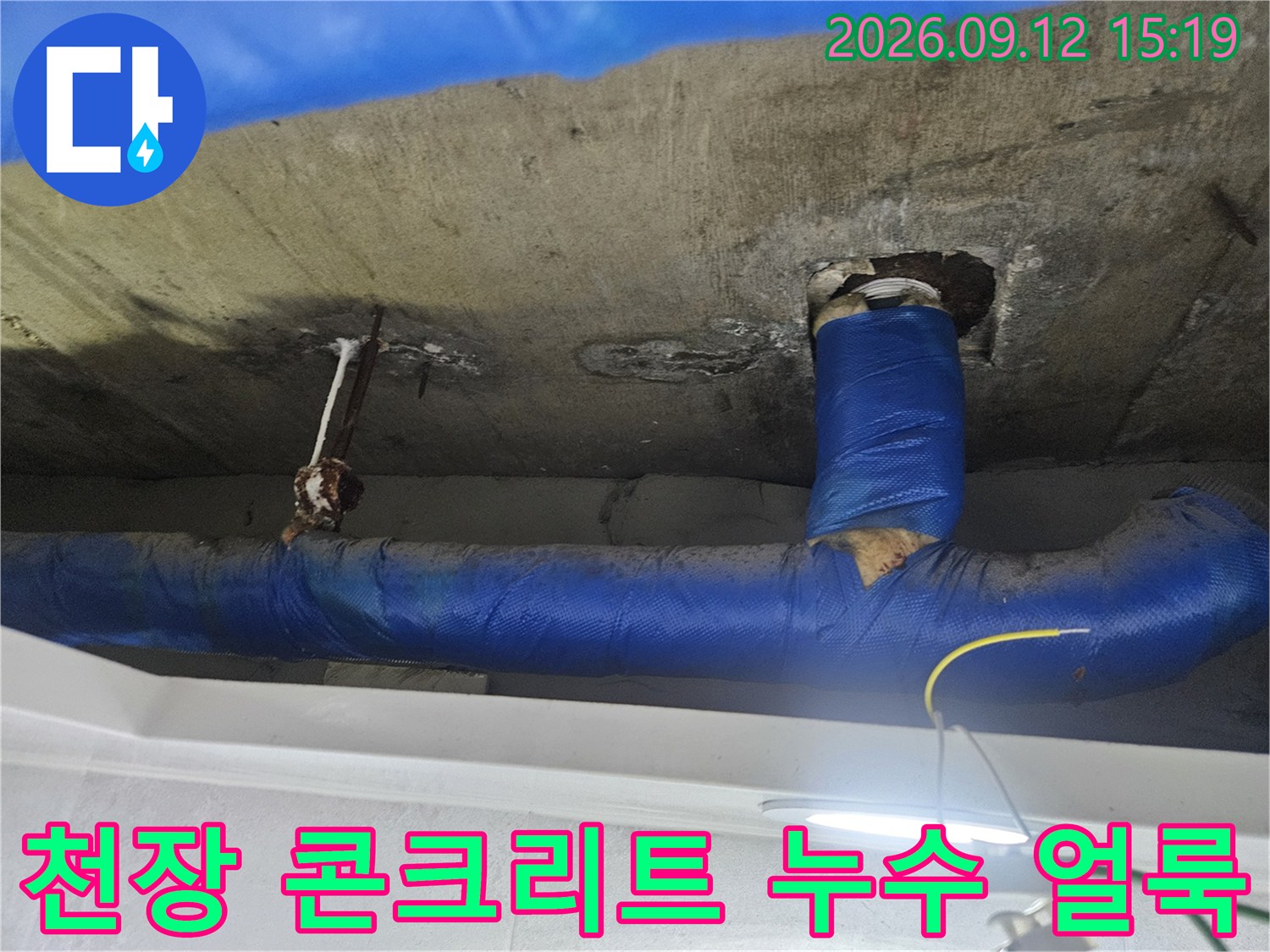젖어있는 천장-콘크리트 면과 파란색 배관 보온재의 근접 촬영입니다.