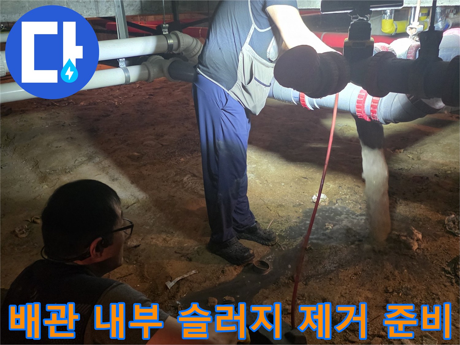 배관 막힘을 해결하기 위해 소제구를 열고 샤프트 장비를 투입하는 장면입니다.