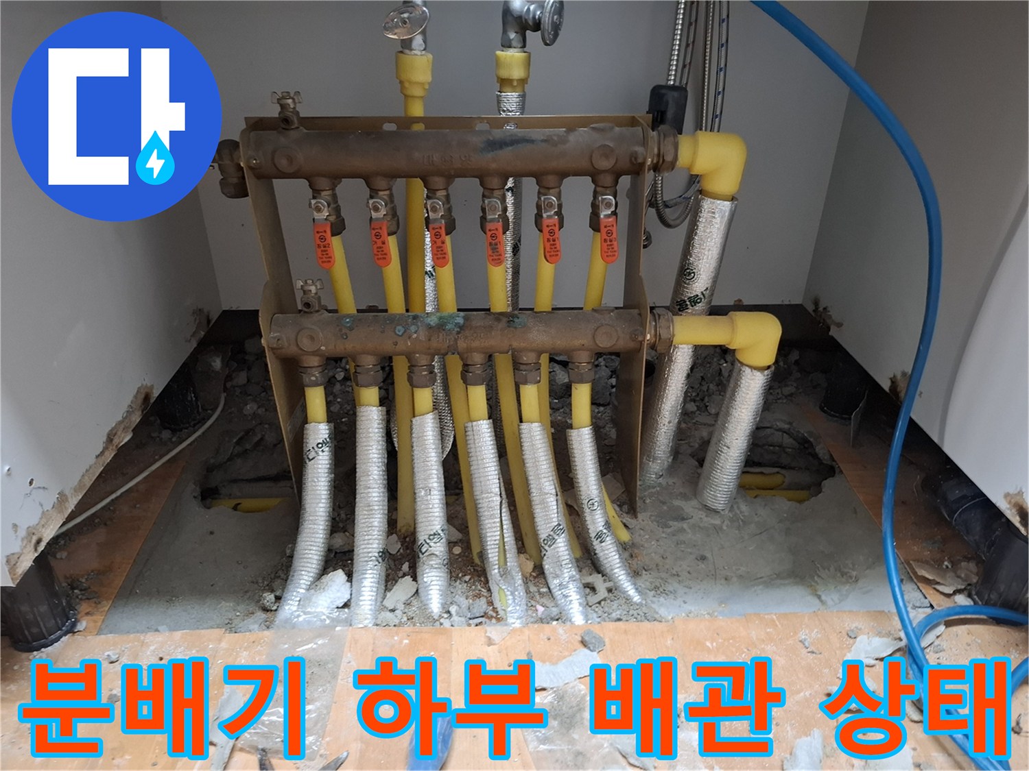 노란색 엑셀 배관과 분배기가 설치된 싱크대 하부 작업 모습